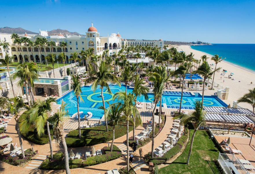 Hotel Riu beach front pool with ocean view and palm trees in Cabo San Lucas, Mexico.