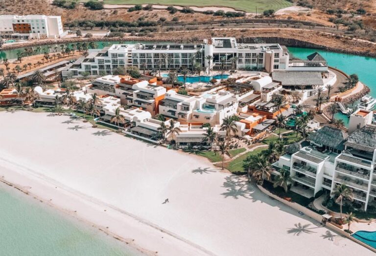 Aerial view of Costa Baja La Paz beach club with white sand and crystal-clear waters.