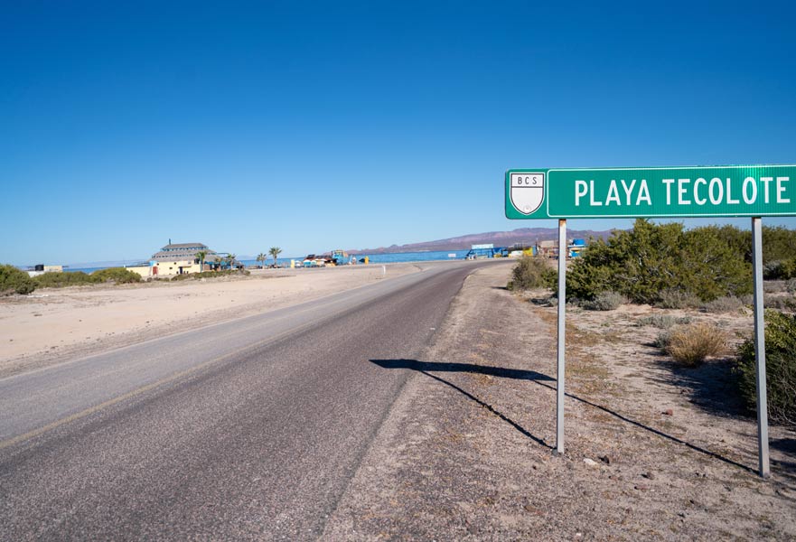 Blue skies with Playa Tecolote entrance sign on the highway.