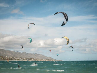 Eight people practicing kitesurf in La Ventana BCS Mexico with colorful kites and the mountains behind.