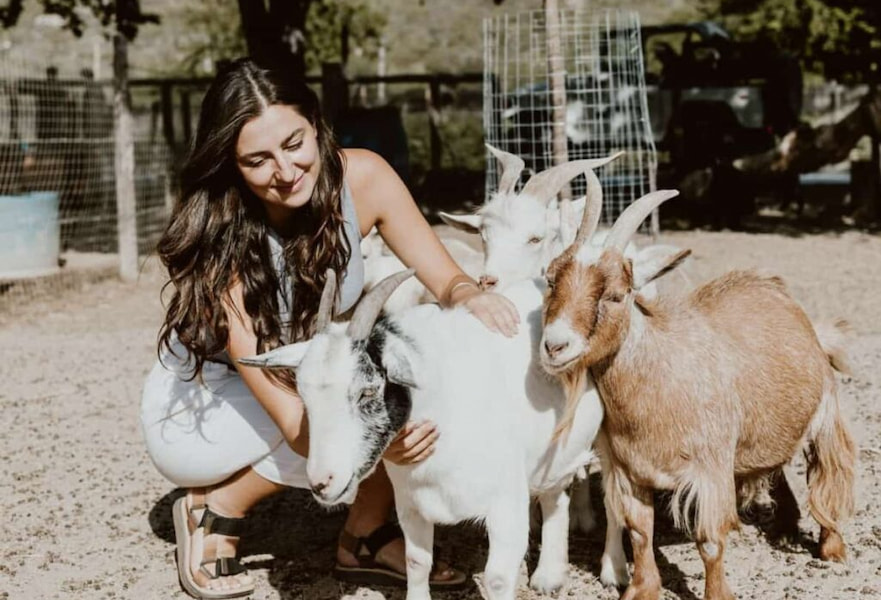 A woman petting three little goats at the animal sanctuary in Acre Treehouse Hotel, Los Cabos, Mexico.