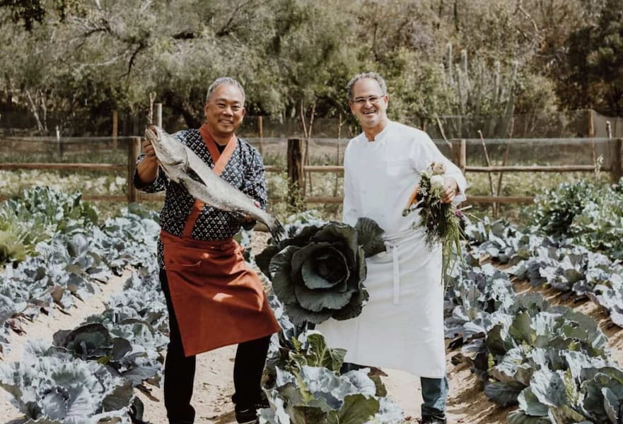 A chef and a seafood cook posing with a big fish and vegetable crops at the Acre farm in Los Cabos, Mexico.