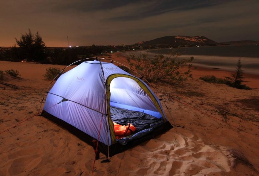 A lighted blue camping tent at the beach during the sunset in La Paz, Baja California Sur, Mexico.