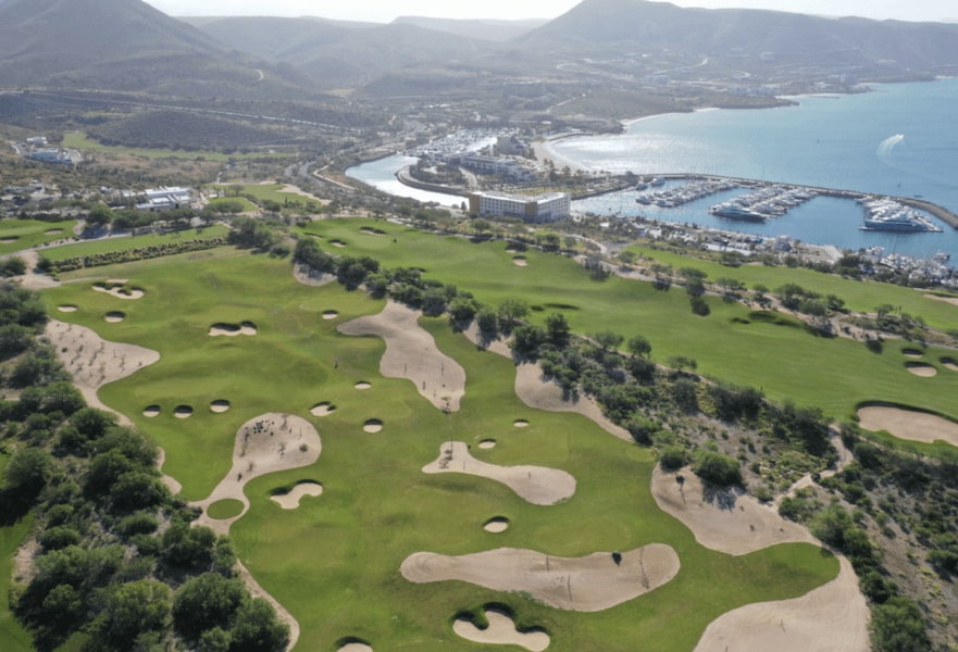 Golf club "El Cortés" at Costa Baja La Paz with large field of greenery, sandy areas, and the marina dock on the back.