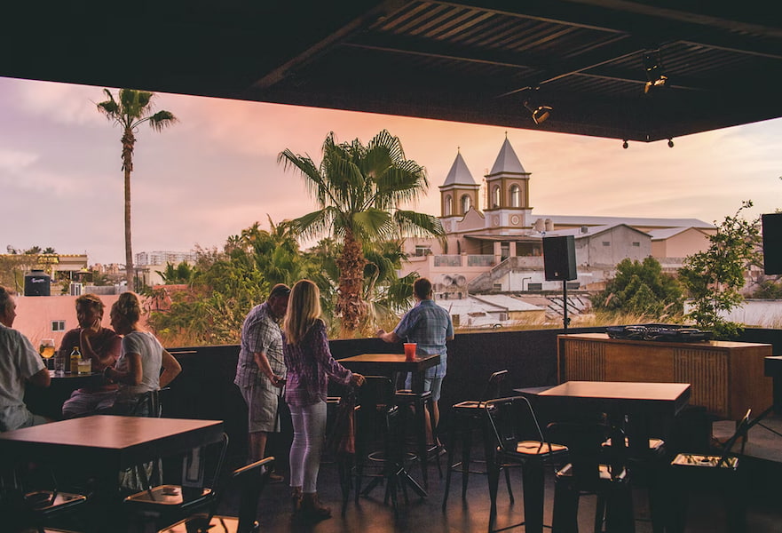 Six people seated at the Dalton Gin Bar terrace with a view of the San José del Cabo downtown.