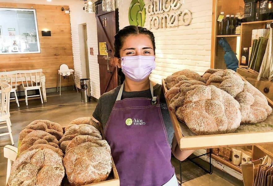 Waitress with purple apron carrying two trays full of traditional Mexican sweet bread in Dulce Romero, La Paz, Mexico.