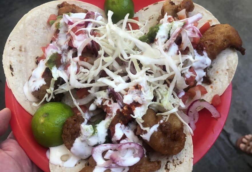 Three fish and shrimp tacos with cabbage, pickled onion and sauce from Albatros taqueria stand in La Paz, Mexico.