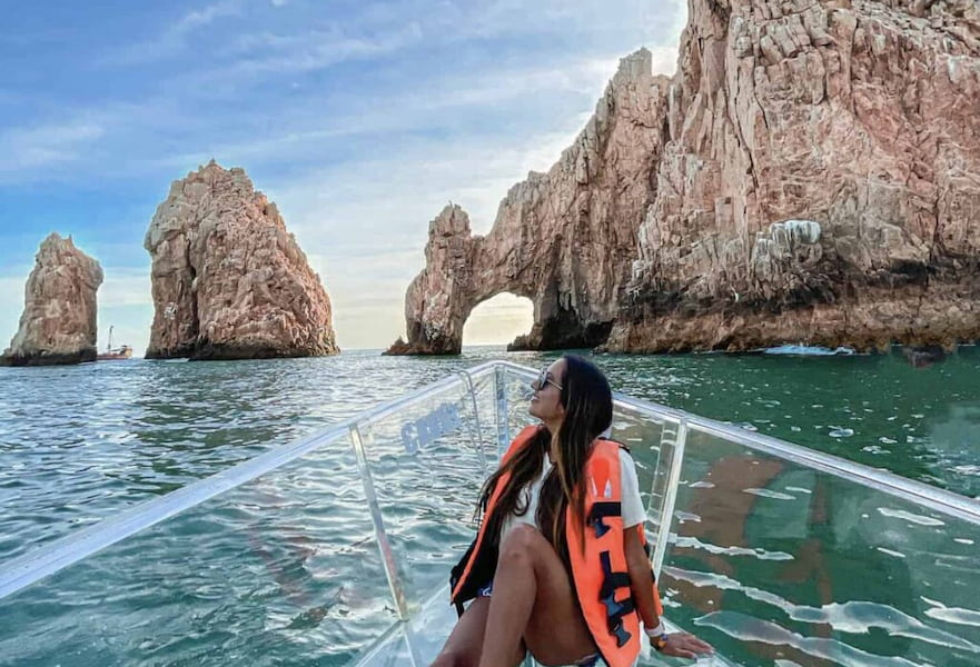 Woman taking a glass-bottomed boat tour looking at The Arc in Los Cabos, Mexico.
