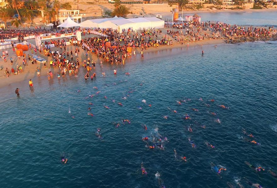 Ironman triathlon race with hundreds of competitors swimming to the end line in Palmilla beach, Los Cabos, Mexico.