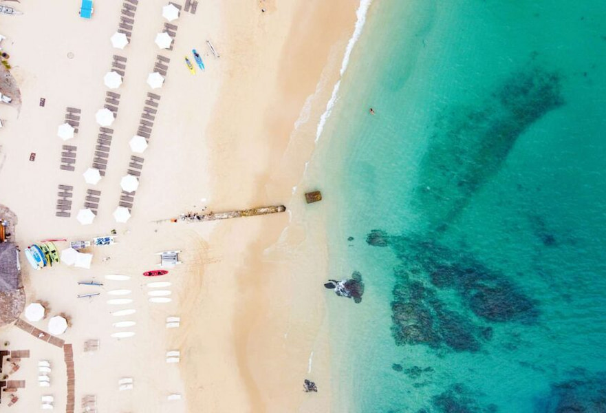 Palmilla beach seashore from above with kayaks and sun loungers on the white sand in San José del Cabo, Mexico.