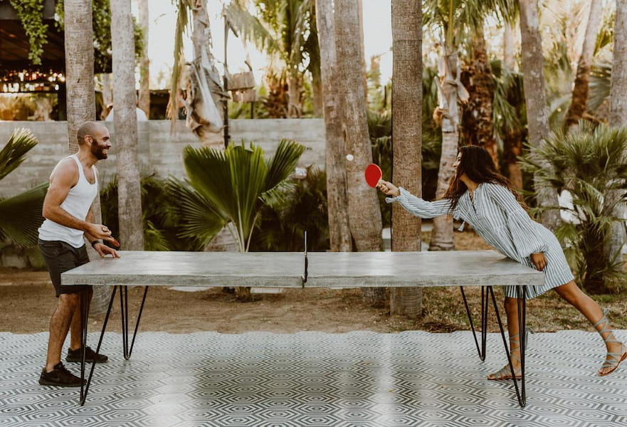 A man and a woman playing in a ping pong table at Acre Treehouse hotel in Los Cabos, Mexico.