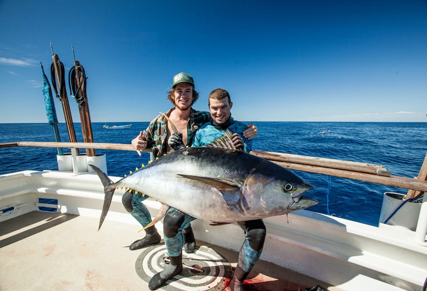 Two males holding a big tuna on their laps after a spearfishing adventure in La Ventana BCS.
