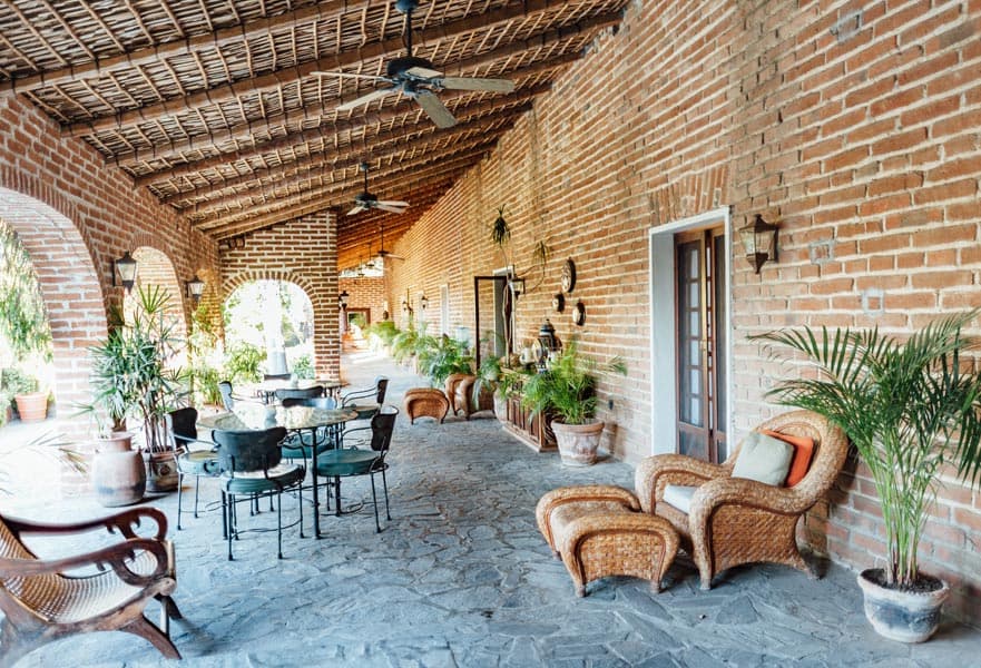 Hacienda-style outdoor seating area with a round table and old fashion chairs at Todos Santos Inn, Mexico.