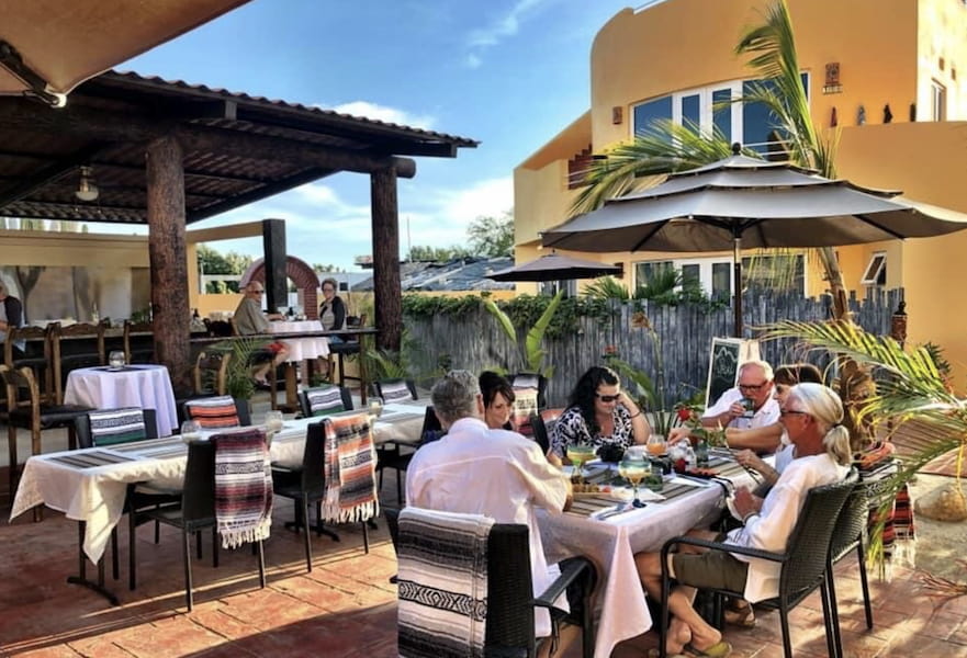 A small group of people seated and having a meal in a sunny day at Casa Maya Restaurant, El Pescadero, BCS, Mexico.