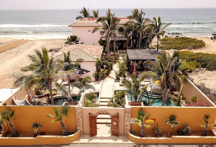 Cerritos Beach Inn main entrance with orange walls, wood doors and palm trees, El Pescadero, Mexico.
