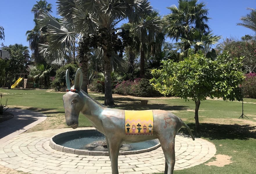 A donkey statue with palm trees and bushes in Flora Farms, Los Cabos, Mexico.