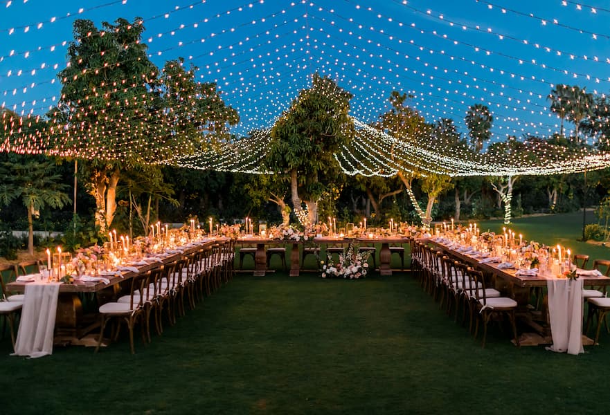 Flora Farms wedding venue with dim lighting and candles and flowers in wooden tables with elegant tablecloths, Los Cabos, Mexico.