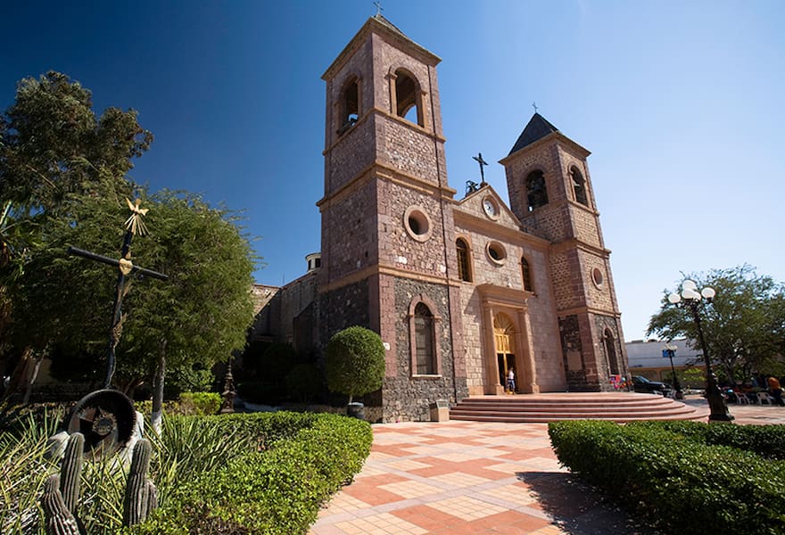 La Paz Mexico Cathedral view on a sunny day surrounded trees and bushes.