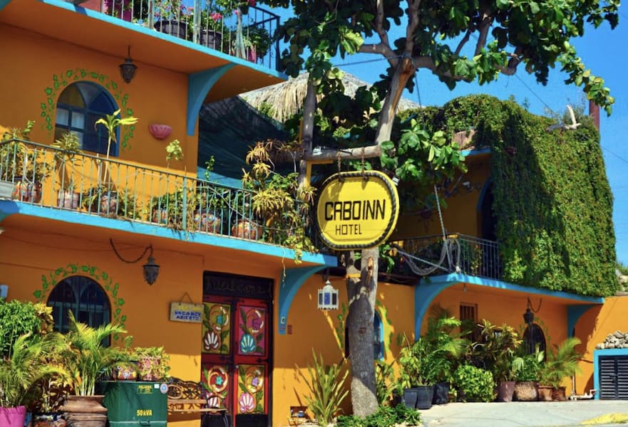 The Cabo Inn main entrance with colourful yellow and blue decoration with plants, Cabo San Lucas, Mexico.