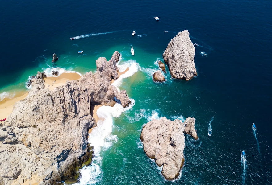 Aerial picture of the rock formation The Arc, sailboats navigating around in Cabo San Lucas, Mexico,
