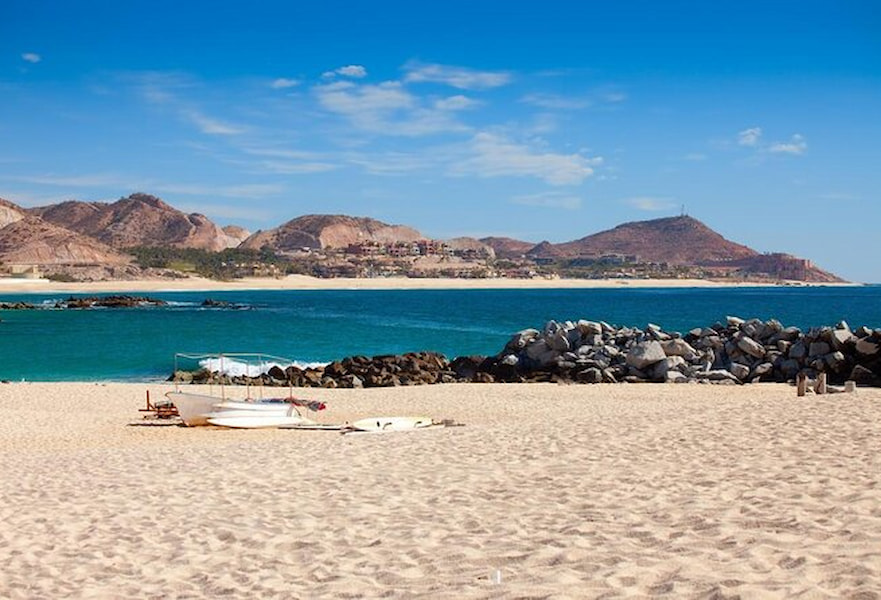 A white boat resting at the Cabo Pulmo coast, with turquoise waters, white sand, and mountains on the back BCS, Mexico