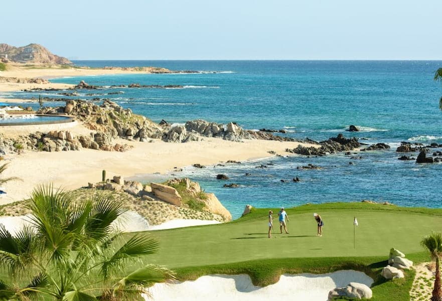 three people playing golf at the Cove Club with ocean views in Cabo del Sol, Mexico.