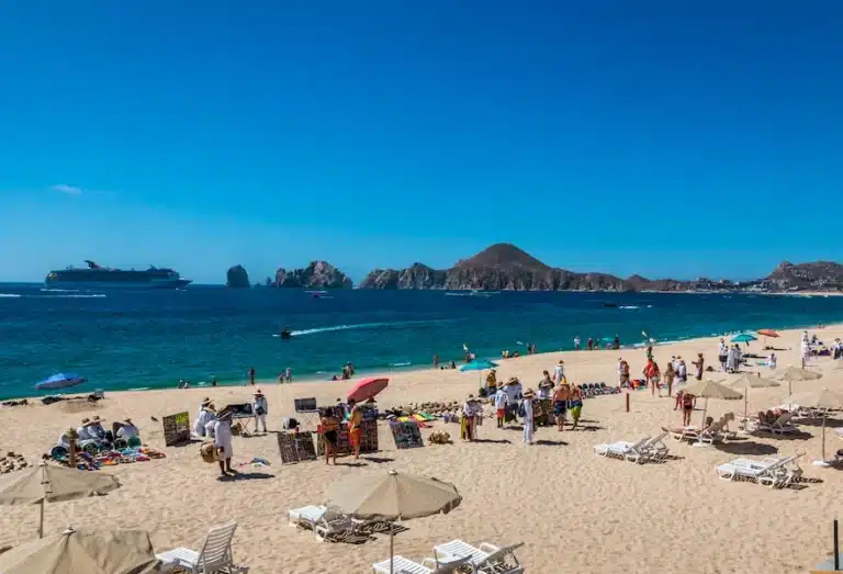 Medano beach with tourists, vendors and chairs and umbrellas.