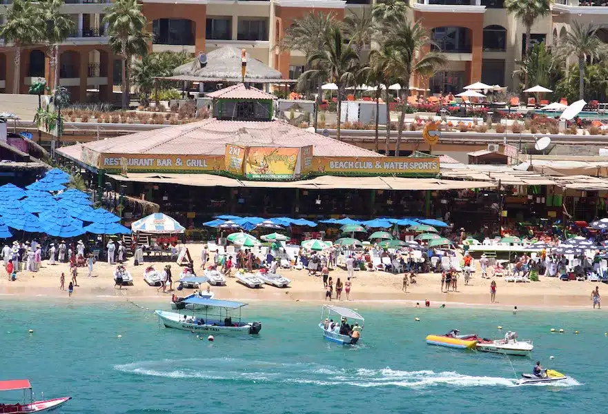 A group of people at Mango Deck on Medano Beach in Cabo San Lucas, Mexico